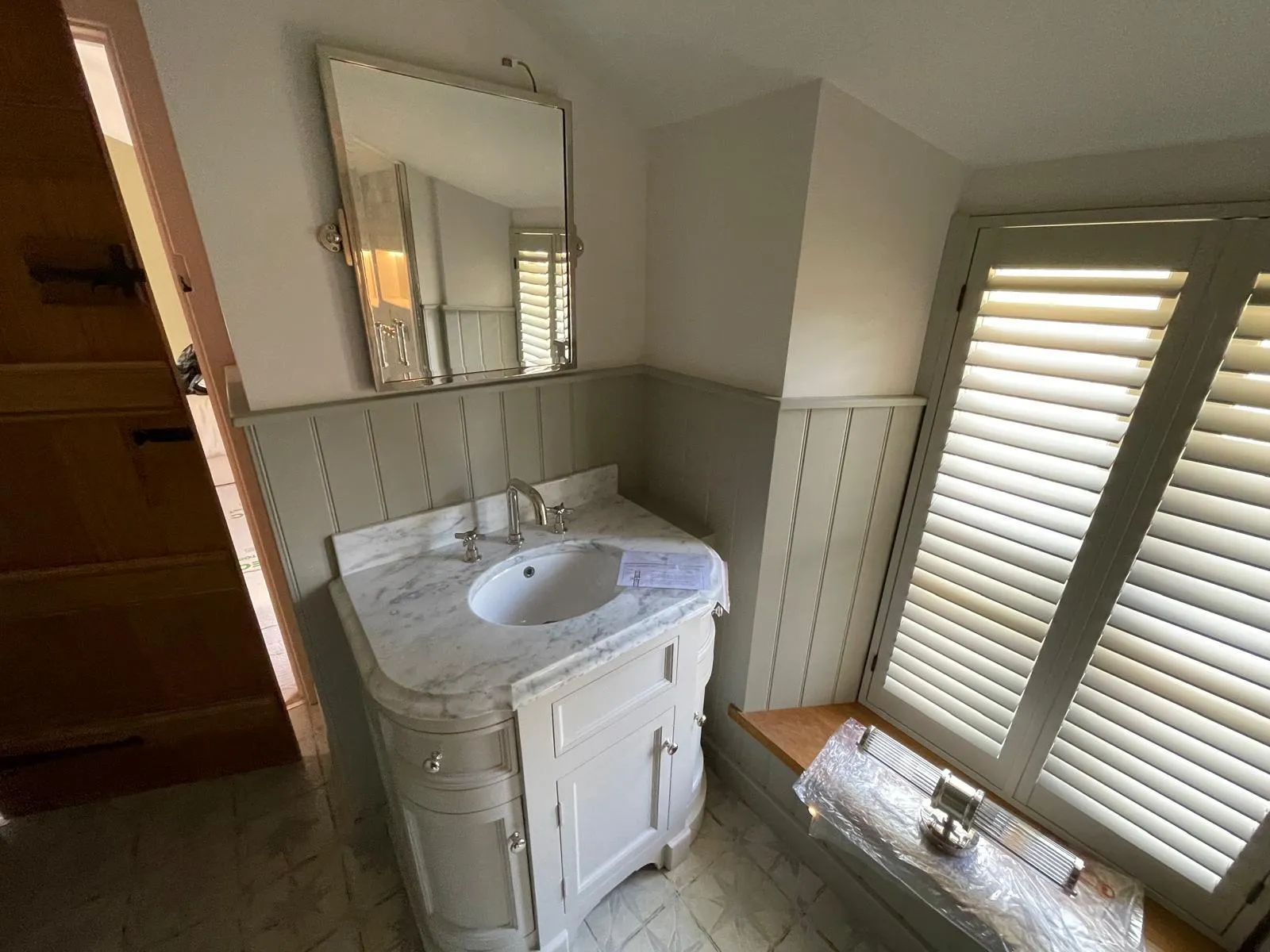 Period bathroom with painted panelling, shutters and a marble vanity