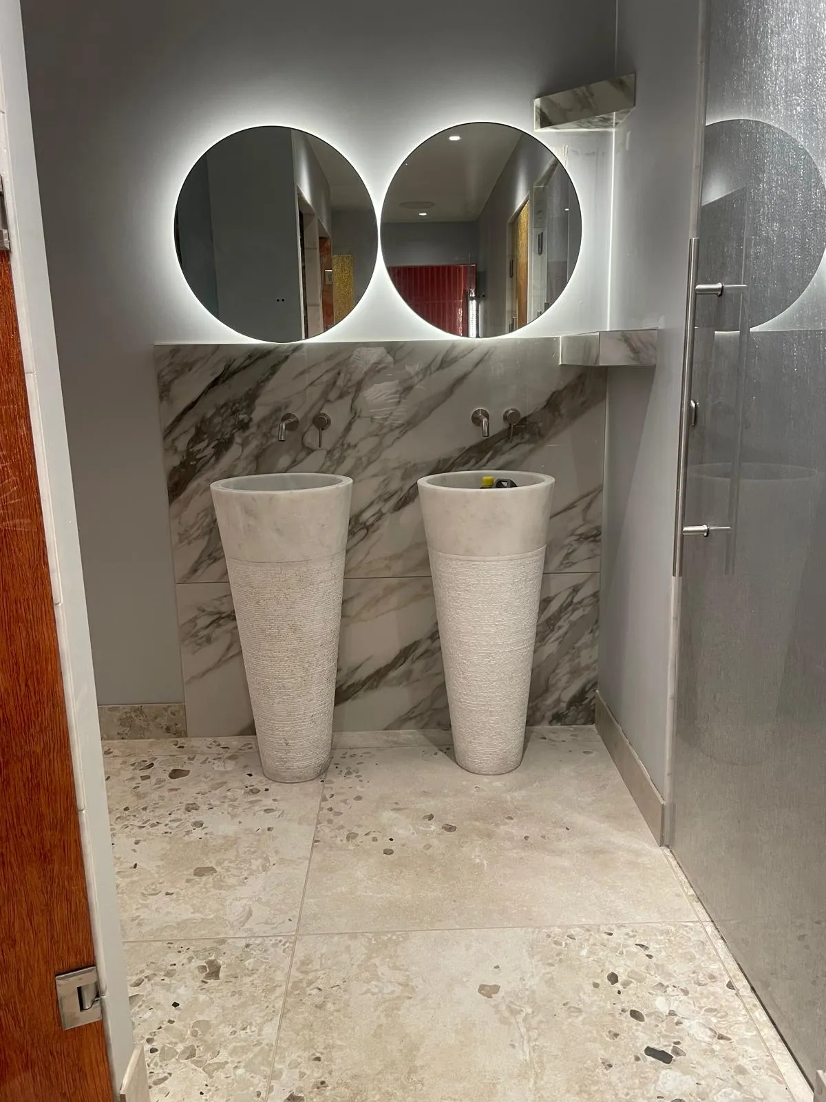 Bathroom with twin stone basins and a marble splashback