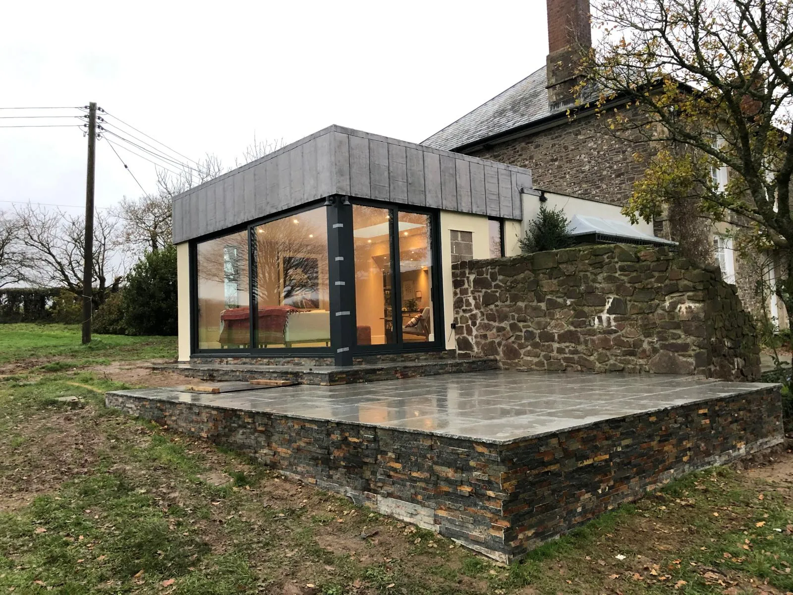 Stone patio and slate-clad plinth outside a glazed extension