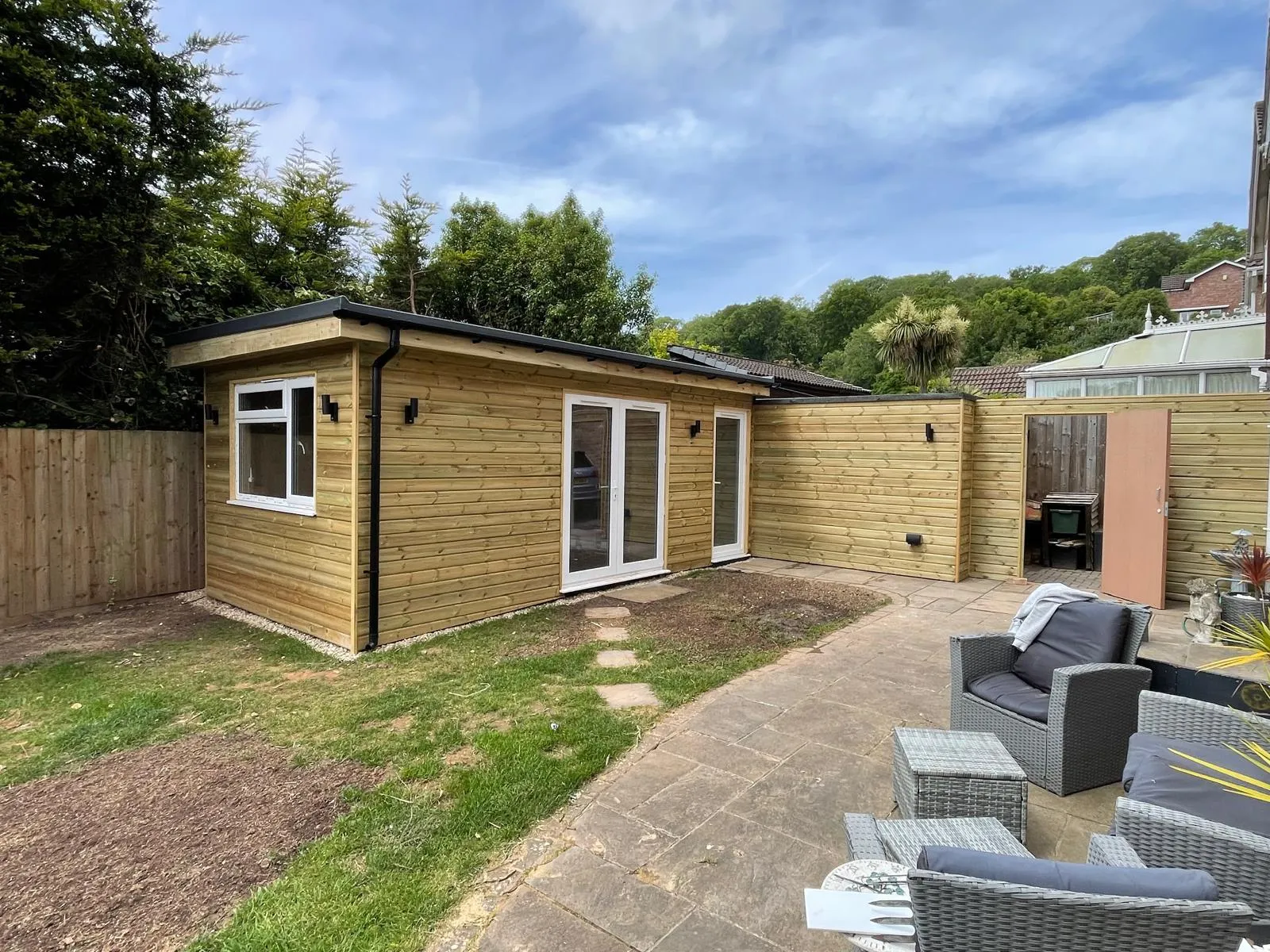 Timber-clad garden room with French doors opening onto a patio