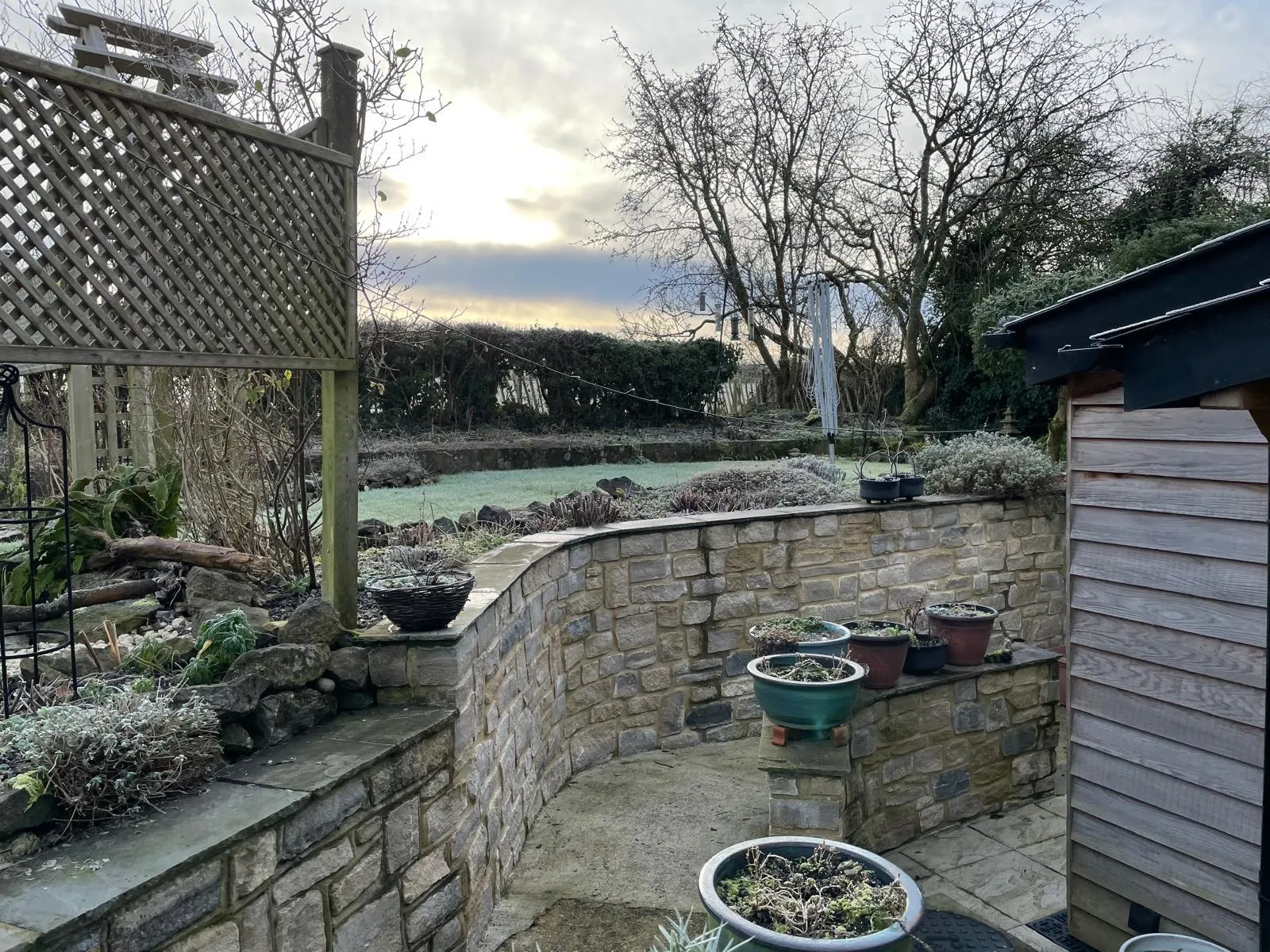 Curved natural stone garden wall and patio on a frosty morning