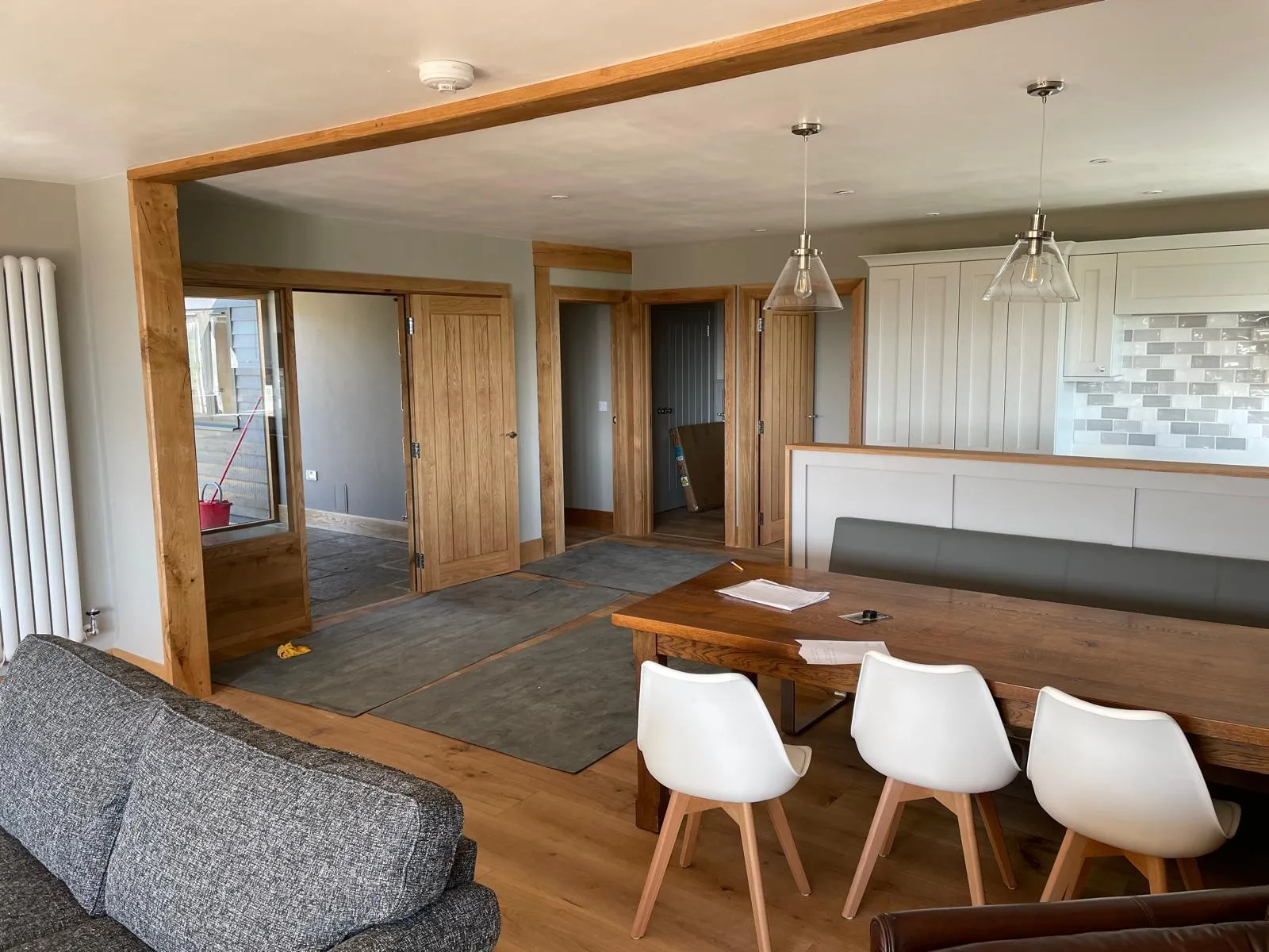 Open-plan kitchen with white shaker units and oak beams